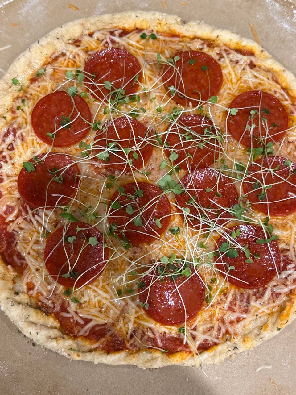 A pepperoni pizza finished with microgreens