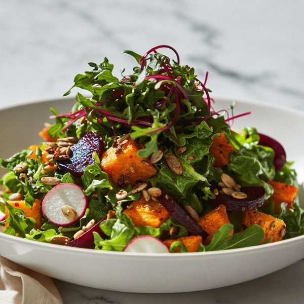 A salad of roasted squash, beets, and radish topped with arugula and beet microgreens
