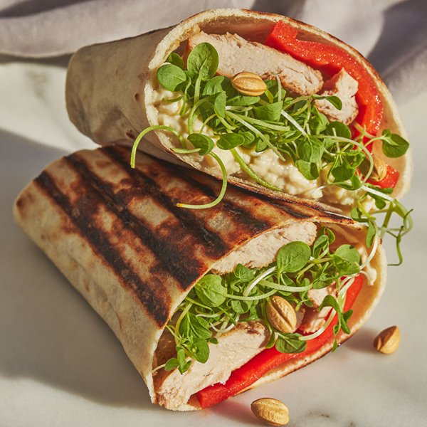 A grilled chicken wrap filled with sunflower and pea shoots